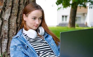 avvicinamento di un' contento femmina con guardare a telecomando.portatile formazione scolastica o opera .all'aperto, dentro il park.back per scuola foto