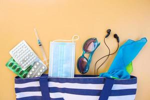 spiaggia Borsa, Da donna Accessori, pillole, siringa e protettivo medico maschera su beige sfondo. superiore Visualizza. foto