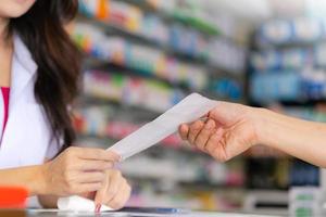 farmacista femminile che legge la prescrizione della medicina a un paziente foto