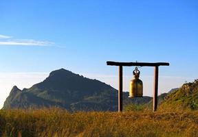 il d'oro o oro antico campana sospeso su alto posto con montagna e chiaro blu cielo sfondo con copia spazio. bellissimo oggetto decorazione con paesaggio Visualizza di natura. punto di riferimento su punto di vista foto