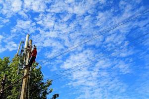 Manutenzione ingegnere o tecnico si arrampica per telecomunicazione polo per riparare, fissaggio, ambientazione su, installazione, cablaggio e analisi antenna o microonde sistema con nube e blu cielo e copia spazio foto