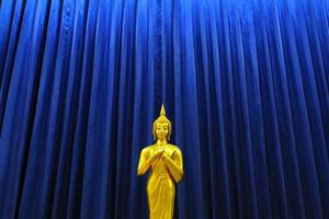 d'oro Budda statua su modello di blu tenda sfondo. religione, fede, buddista e antico, oro oggetto con copia spazio. foto