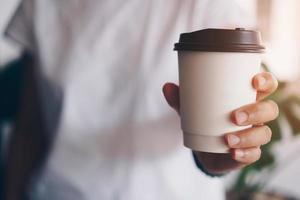 mano che tiene una tazza di caffè con luce solare flare foto