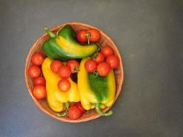 peperoni e pomodori in un cesto di vimini su uno sfondo di tavolo scuro