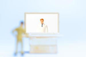 persone in miniatura di un paziente di sesso maschile che si consulta con un medico utilizzando la videochiamata su un computer portatile, concetto medico in linea