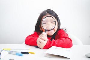 il poco ragazza gode studiando scienza. lei detiene un' ingrandimento bicchiere. concetto di bambino formazione scolastica sviluppo foto