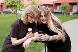 Due divertente ragazze siamo seduta su un' swing nel il città e assunzione selfie su loro Telefono. adolescenti Sorridi foto