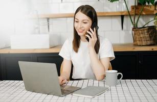 attività commerciale donna avere il gioia di parlando su il smartphone, tavoletta e portatile il casa ufficio foto