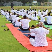 nuovo delhi, India, giugno 21 2022 - gruppo yoga esercizio sessione per persone a yamuna gli sport complesso nel delhi su internazionale yoga giorno, grande gruppo di adulti frequentando yoga classe nel cricket stadio foto