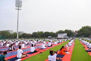 nuovo delhi, India, giugno 21 2022 - gruppo yoga esercizio sessione per persone a yamuna gli sport complesso nel delhi su internazionale yoga giorno, grande gruppo di adulti frequentando yoga classe nel cricket stadio foto