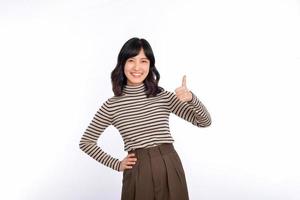 giovane fiducioso asiatico donna con maglione panni mostrando pollice su nel approvazione, consigliando, in piedi isolato su bianca sfondo foto