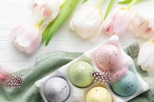 titolare con Pasqua uova dipinto pastello colori su un' bianca di legno sfondo. foto