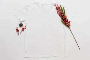 vicino su bianca vuoto modello t camicia con copia spazio e Natale vacanza concetto. superiore Visualizza modello maglietta e rosso vacanze decorazioni su bianca sfondo. contento nuovo anno Accessori. natale attrezzatura foto