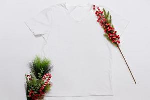 vicino su bianca vuoto modello t camicia con copia spazio e Natale vacanza concetto. superiore Visualizza modello maglietta e rosso vacanze decorazioni su bianca sfondo. contento nuovo anno Accessori. natale attrezzatura foto