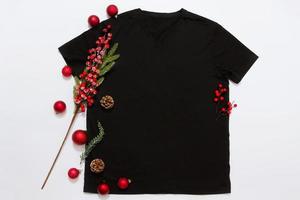 vicino su nero vuoto modello t camicia con copia spazio e Natale vacanza concetto. superiore Visualizza modello maglietta e rosso vacanze decorazioni su bianca sfondo. contento nuovo anno Accessori. natale attrezzatura foto