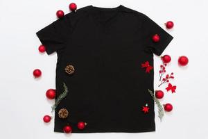 vicino su nero vuoto modello t camicia con copia spazio e Natale vacanza concetto. superiore Visualizza modello maglietta e rosso vacanze decorazioni su bianca sfondo. contento nuovo anno Accessori. natale attrezzatura foto