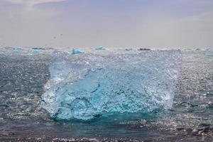 Diamond Beach in Islanda con iceberg blu che si sciolgono sulla sabbia nera e ghiaccio che brilla di luce solare. foto