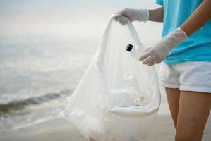 volontario raccogliere su spazzatura spazzatura a il spiaggia e plastica bottiglie siamo difficile decomporsi impedire danno acquatico vita. terra, ambiente, greening pianeta, ridurre globale riscaldamento, Salva mondo foto