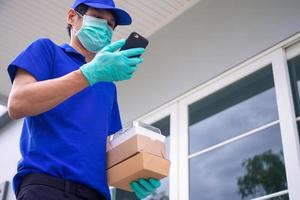 il maschio consegna personale in piedi a il porta indossa un' uniforme con un' maschera e guanti consegnare cibo secondo per ordini quello i clienti chiamata per ordine. servizio in linea ordine cibo concetto. foto