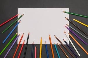 matite colorate e carta bianca su sfondo nero foto