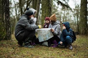 famiglia e bambini con carta geografica nel il foresta. foto