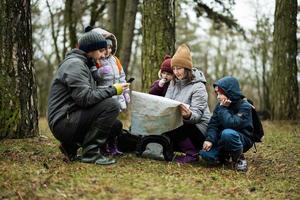 famiglia e bambini con carta geografica nel il foresta. foto