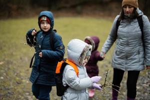 madre con bambini Tenere salice ramoscelli mentre in viaggio nel foresta. foto