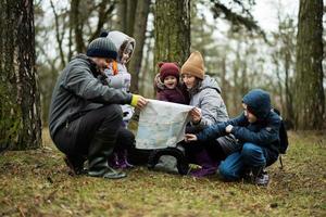 famiglia e bambini con carta geografica nel il foresta. foto