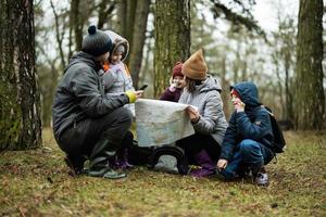 famiglia e bambini con carta geografica nel il foresta. foto