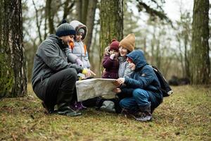 famiglia e bambini con carta geografica nel il foresta. foto