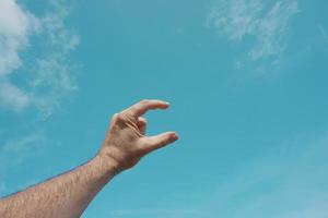 mano su Esprimere a gesti nel il blu cielo, sentimenti e emozioni foto