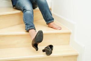 donna asiatica d'affari dolore alla caviglia, piede con crampi alle gambe e caduta dalle scale perché superfici scivolose in ufficio. foto