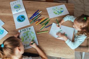 bambini disegnare il pianeta terra con matite e pennarello penne su album lenzuola per terra giorno a loro casa tavolo. il concetto di proteggere il ambiente, pace su terra foto