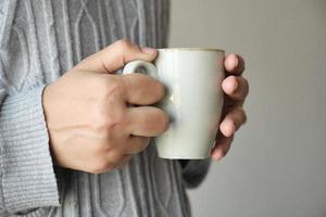 primo piano della mano delle donne che tiene la tazza da caffè foto