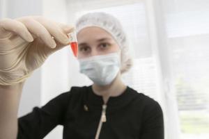 un' test tubo con un' sangue test su il sfondo di un' sfocato medico laboratorio assistente. foto