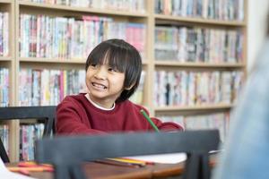 asiatico ragazzo scrittura nel taccuino, fare compiti a casa nel un' aula a scuola. formazione scolastica concetto. foto