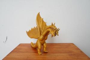 d'oro Drago ghidorah isolato su bianca sfondo. su di legno tavolo foto