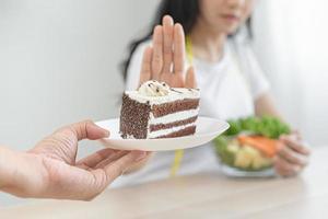 dieta, dieta malsano asiatico giovane donna mano nel spingere fuori, rifiutando mangiare cioccolato torta o dolce gusto, combattente per mantenere esso a partire dal ottenere Grasso quando persona portare per me. sano, nutrizione di peso perdita foto