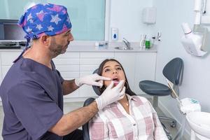 professionale maschio ortodontista l'applicazione fermo su denti di femmina paziente foto