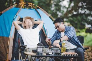 asiatico rilassato uomo utilizzando smartphone e in attesa per il suo amico cucinando foto