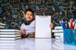 bambino seduto e mostra la lavagna degli appunti in classe foto