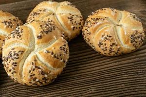 totale Grano pane su di legno sfondo. mazzo di Kaiser rotoli con sesamo. foto