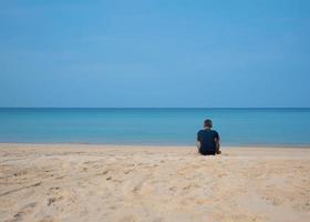 un' anziano asiatico maschio seduta su il spiaggia foto