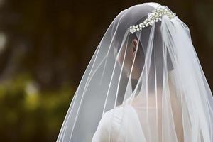 vicino su dettaglio un' sposa a partire dal dietro a nel un' bianca nozze vestire. foto