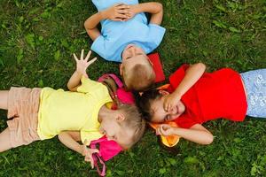 gruppo di contento allegro bellissimo bambini dire bugie su erba nel parco, all'aperto, Italia foto