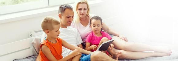 contento famiglia su letto con morbido cuscini a casa foto