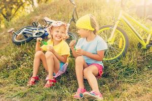 Due bambini equitazione un' bicicletta nel il giardino foto