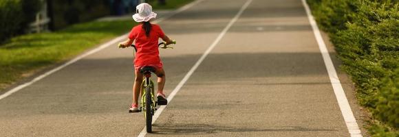 bambini che imparano a guidare una bicicletta su un vialetto fuori. bambine in sella a biciclette su strada asfaltata in città foto