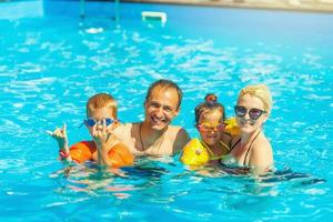 famiglia felice che gioca in piscina. concetto di vacanza estiva foto