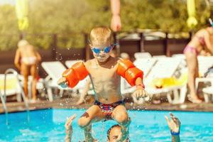 padre e figlio divertente nel acqua piscina sotto sole leggero a estate giorno. tempo libero e nuoto a vacanze. foto